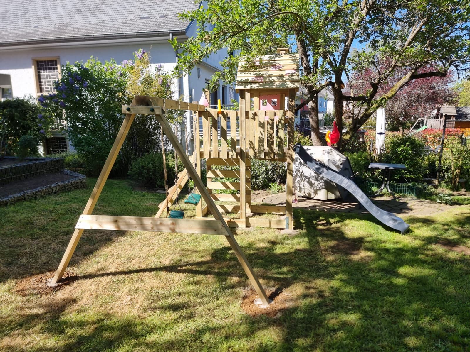 Structure de jeux en bois avec balançoires et toboggan sur une pelouse, installation Green Space