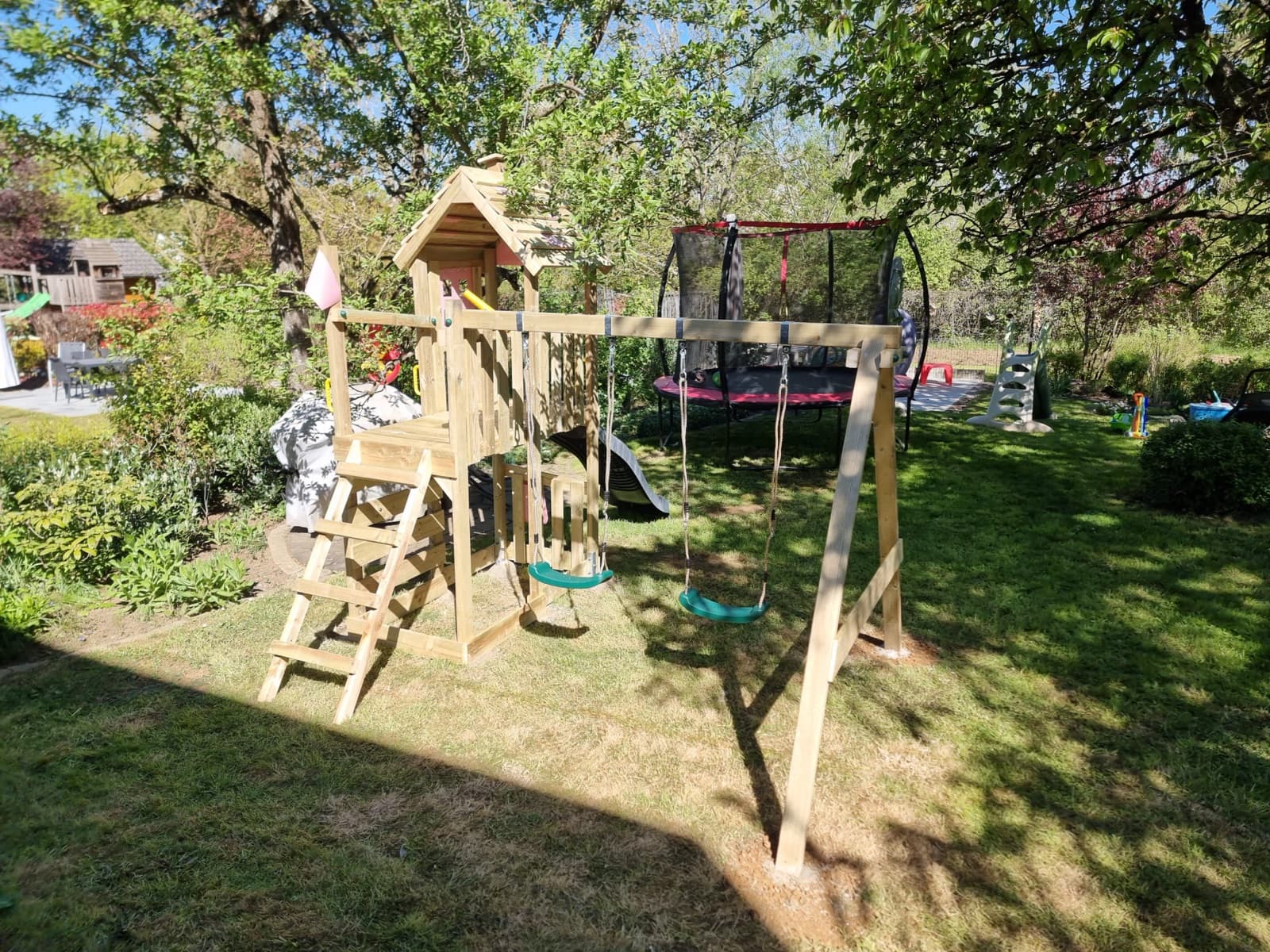 Aire de jeux en bois avec portique et toboggan près d'un trampoline, installation Green Space