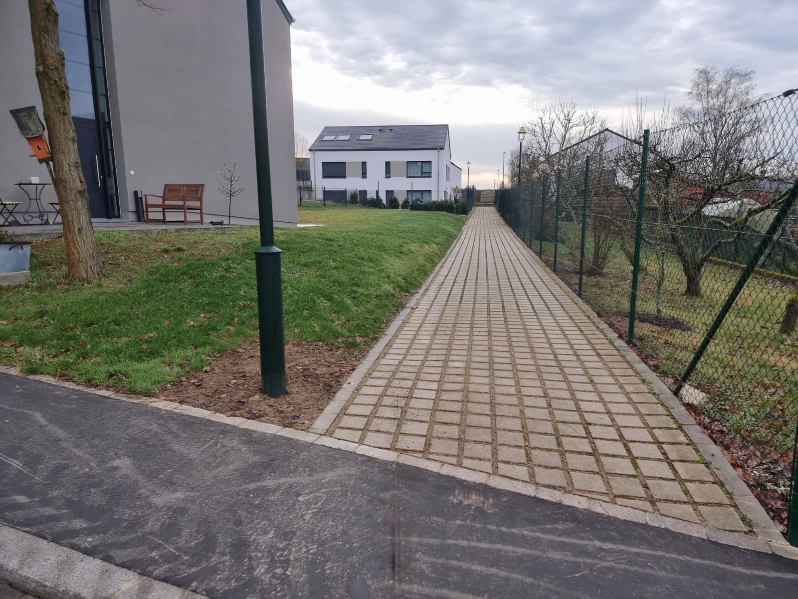 Allée en pavés serpentant le long d'une clôture dans un jardin aménagé par Green Space