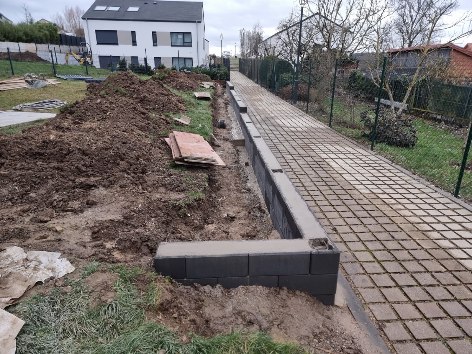 Mur de soutènement en blocs béton anthracite le long d'une allée pavée, réalisation Green Space