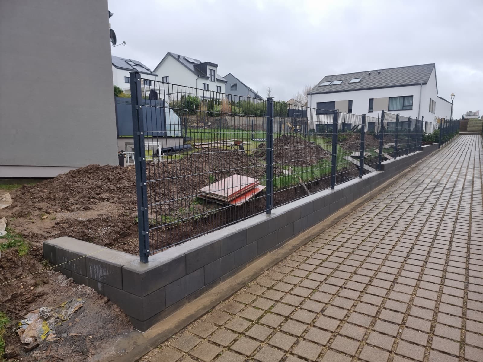 Clôture double fil anthracite sur muret le long d'une allée pavée, réalisation Green Space