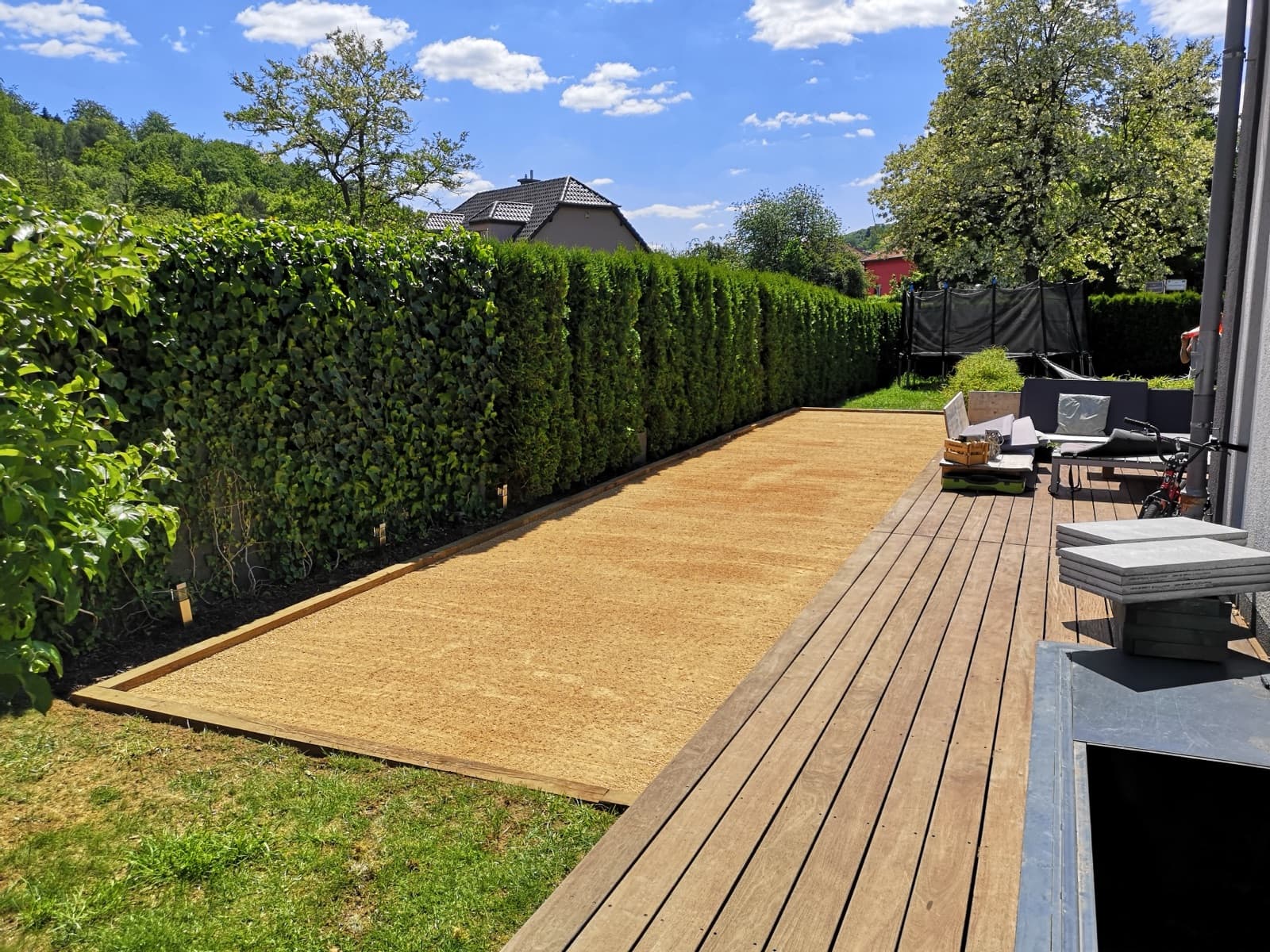 Terrain de pétanque en sable bordé d'une terrasse en bois, réalisation Green Space