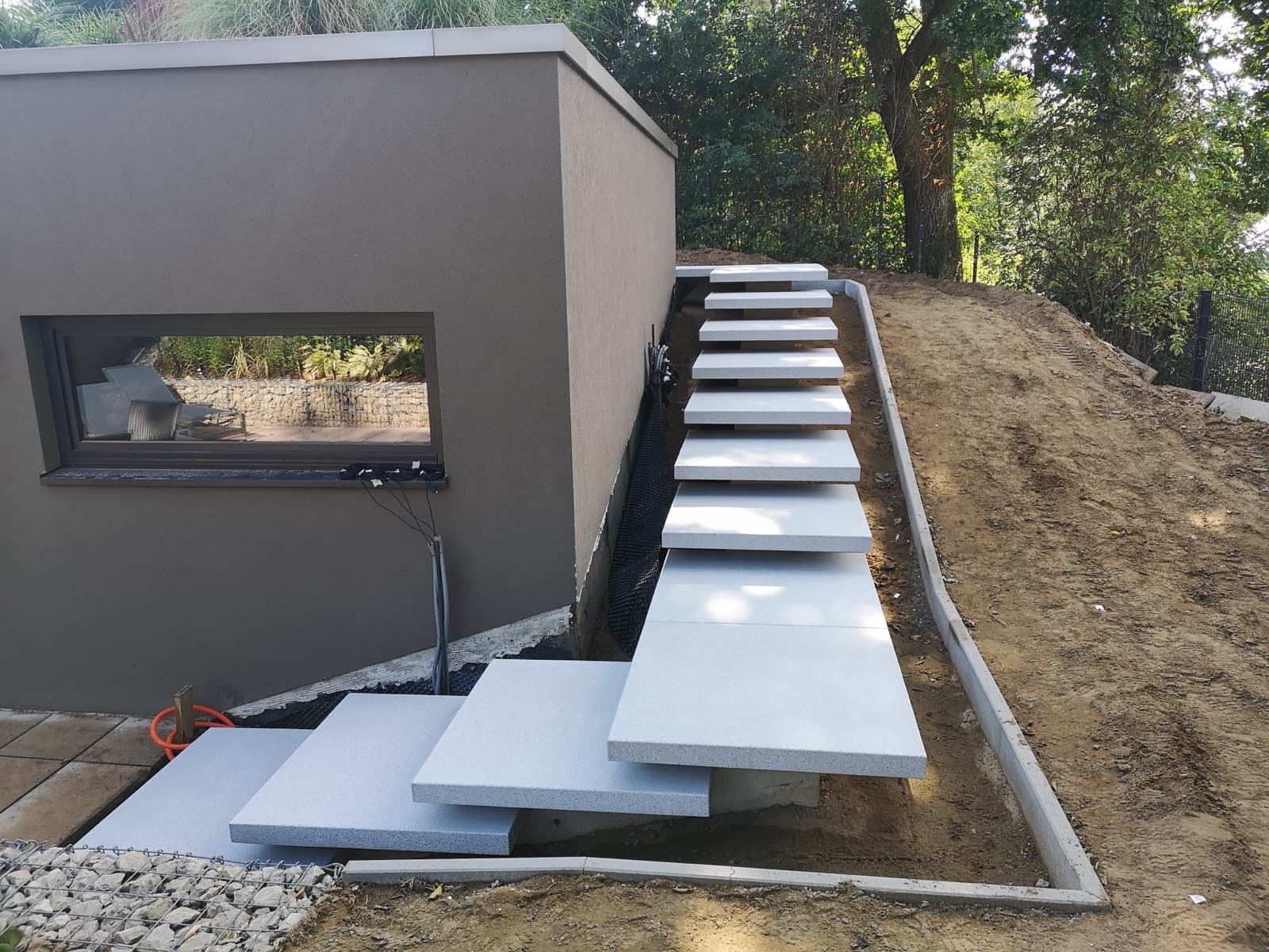 Escalier suspendu en dalles de granit le long d'une pente engazonnée, réalisation Green Space