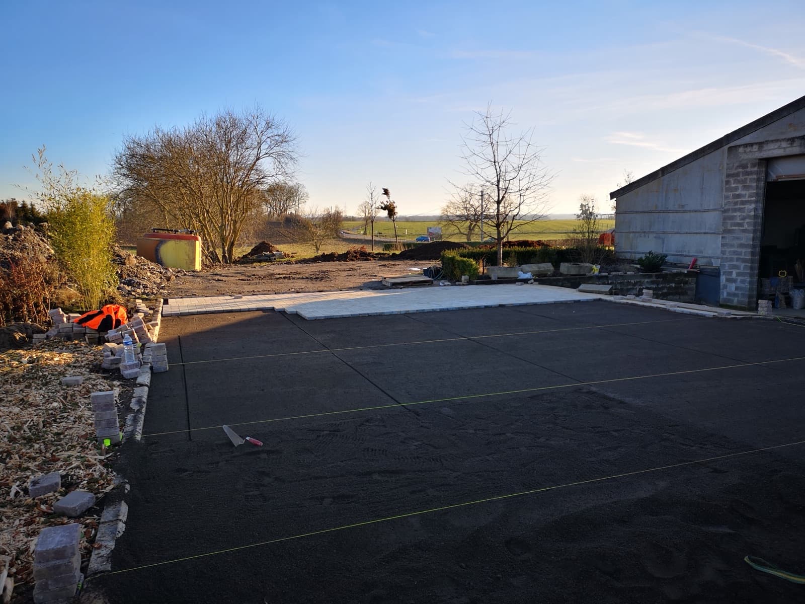 Pose de pavés clairs sur lit de sable lors d'un chantier d'aménagement Green Space